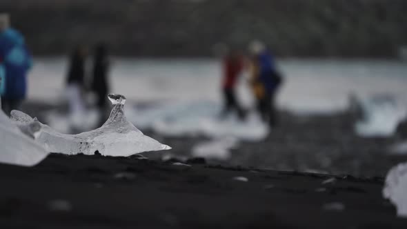 Icebergs on Black Sand Beach with Blurred Tourist in the Background