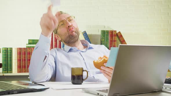 Middleaged Man is Lounging in the Office  He Eats Unhealthy Food Makes a Paper Airplane and Flies It alt