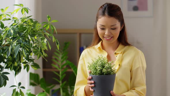 Happy Asian Woman with Flower in Pot at Home alt