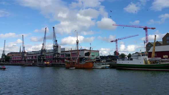 Slow pan of harbor with old cranes and warehouse behind alt