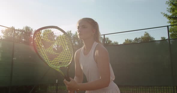 Strong Fit Woman Standing with Racket Waiting for Tennis Ball Looking Concentrated and Serious