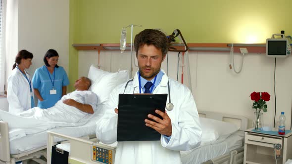 Doctor reading report while nurse interacting with patient in background alt