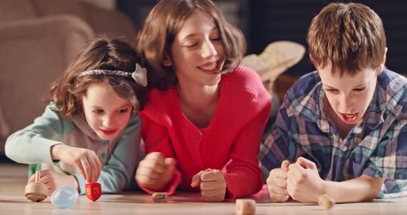 Kids playing with dreidels during Hanukka at home alt