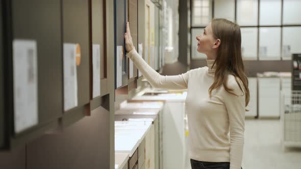 Young Woman in Shop Choosing Material for Facades for Kitchen Furniture alt