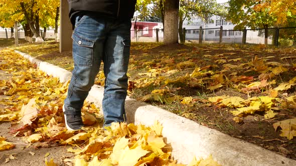 Unrecognizable Child's Feet Walk on Fallen Yellow Autumn Leaves