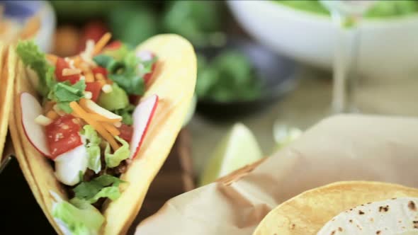Ground beef tacos with romaine lettuce, diced tomatoes, radishes, and shredded cheddar cheese. alt