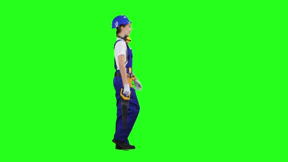 Engineer Girl Carries in a Hand Saw for Its Builders, Green Screen, Side View alt