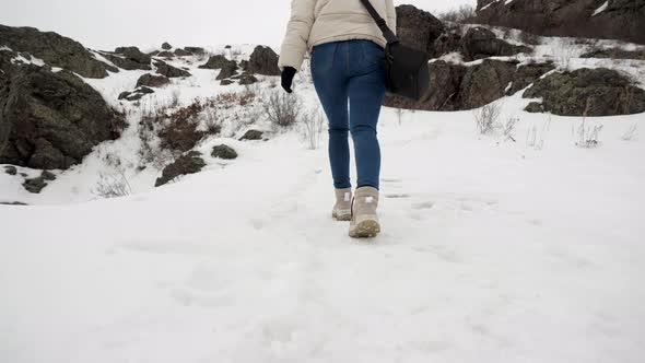 The View From Below is a Girl Tourist Climbing Up to the Top of a Snowy Mountain