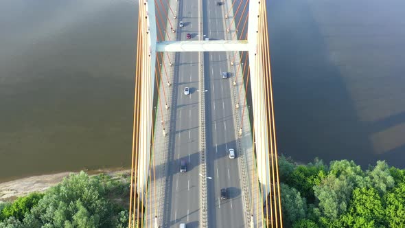 Aerial view of car traffic on modern bridge over river in city in summer day alt