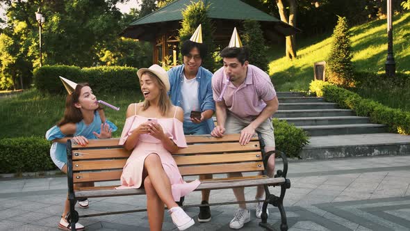 Female Using Cell Phone Sitting on Bench in Park alt