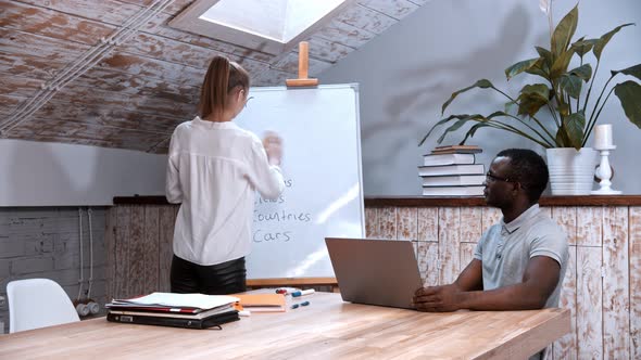 An English Lesson - Woman Cleaning the Board and a Black Man Sitting By the Table alt