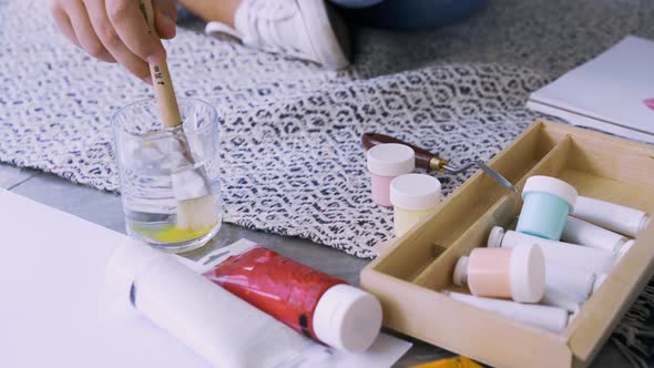 Woman Artist Washes Brush in Glass