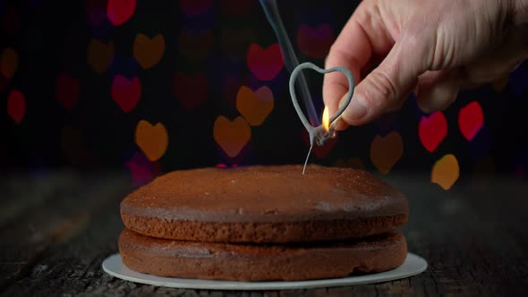 Hand Igniting Heart Shapped Sparkler Placed on a Simple Cake to Celebrate Valentines Day