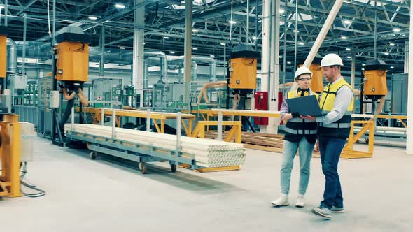 Two Workers in Safety Wear are Walking Along the Fiberglass Factory alt