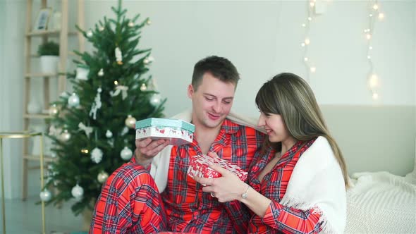 Man and Woman Exchanging Christmas Gifts at Home alt