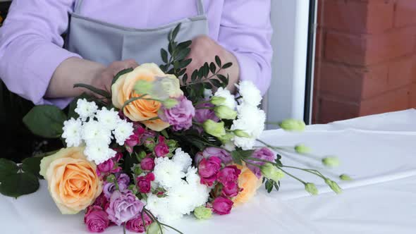 Close up florist hands working in flower shop studio. Floristry creating flower arrangement.