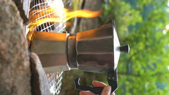 Young Woman Making Coffee on Camp Fire with Moka Pot. A Vertical Video. alt