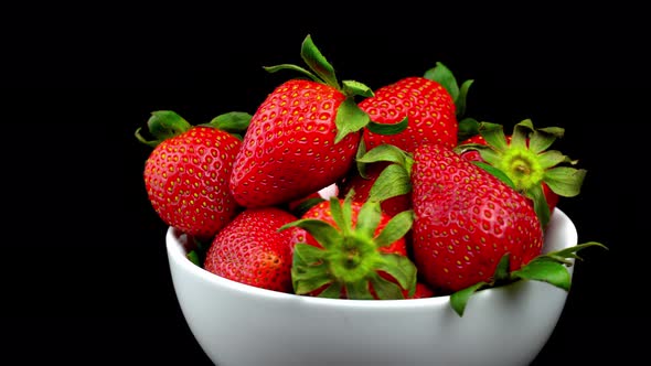Appetizing strawberries with wilted green leaves lie on white porcelain bowl alt