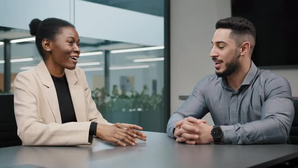 Arabic Businessman and African Businesswoman Talking at Office Table alt