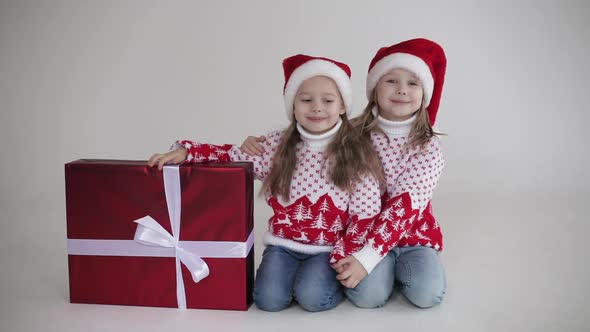 Pretty Sisters Sits Near the Big Red Box with Christmas Present Together