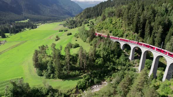 Aerial View of a Moving Red Train Along the Landwasser Viaduct in Swiss Alps alt
