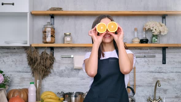 Adorable Playful Vegan Housewife Posing with Slice Fresh Orange on Eyes Having Fun Zoom in Shot alt