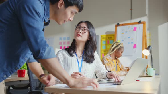 Asian staff creative senior designer coworkers consulting in office on how to solve a problem alt