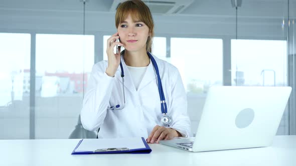 Young Female Doctor Talking on Phone in Hospital alt