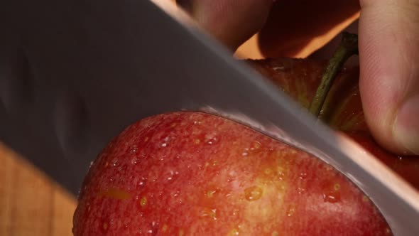 Very sharp knife cuts a slice out of a red apple, macro shot. Detailed close up in 4K. alt