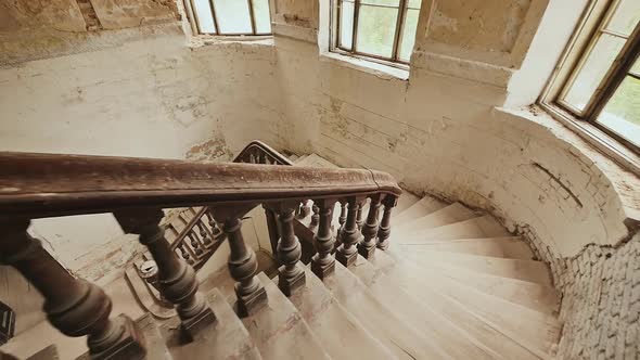 A Staircase with a Dark Wooden Railings in an Abandoned Architectural Building alt