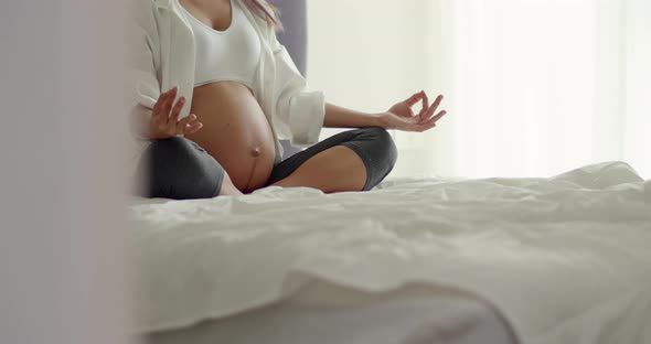 Asian healthy pregnant woman practicing yoga in the bedroom at home.