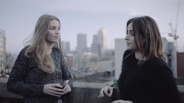 Young adult women talking and drinking on rooftop party