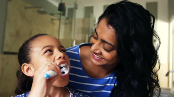 Mother teaching her daughter to brush her teeth in bathroom 4k alt