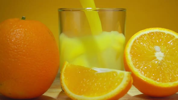 Orange Juice Is Poured in a Glass Next To Ripe Oranges on the Yellow Background alt