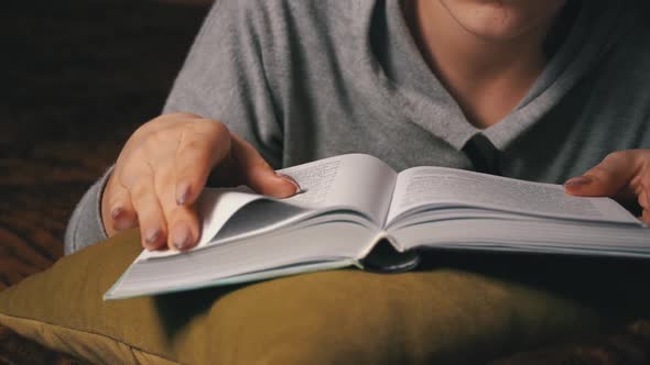 Cute Girl Reads and Leafs Through a Book While Lying Comfortably in Bed alt