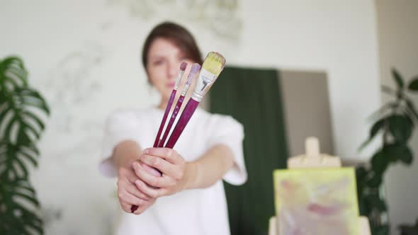 The Artist Shows the Brushes to the Camera alt