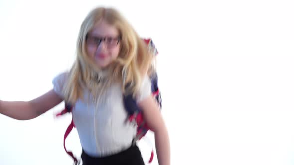 Beautiful Schoolgirl with a School Backpack and Wearing Glasses Dancing in the Studio on a White