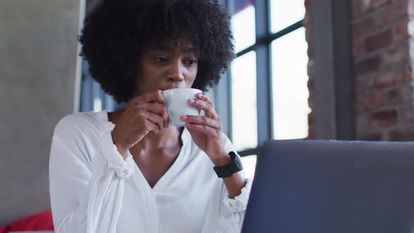 Happy african american woman sitting in cafe drinking cup of coffee and smiling alt