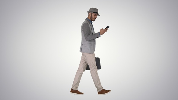 Casual man texting on phone and walking on gradient background. alt
