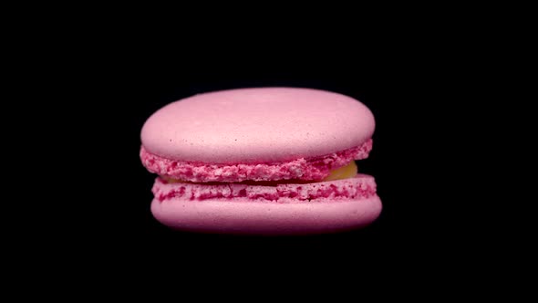 Pink Macaroon Rotating on a Black Background. Food Concept. Sweets Close up on a Turntable alt