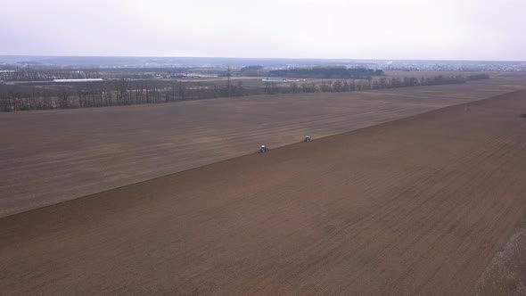 Agricultural Work in the Field, Two Blue Tractors Plow the Land