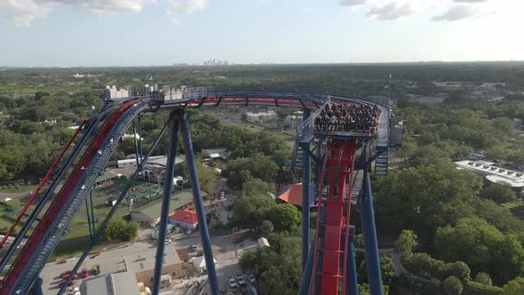 Kids and teenagers having fun riding an extreme roller coaster in theme park. Aerial view alt