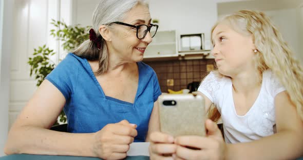 Grandmother and Granddaughter with Smartphone Hugging