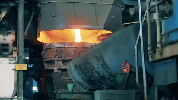 Industrial Tank with Melted Copper Pouring Into It alt