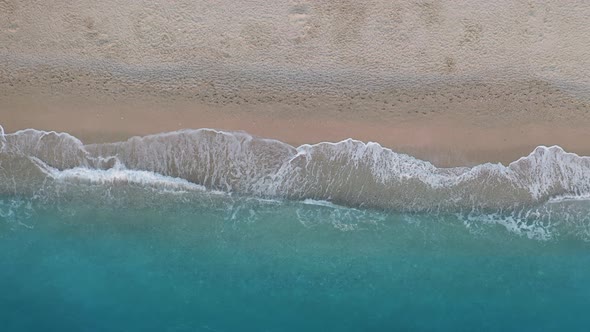 Top Down View of Sandy Beach and Turquoise Sea Waves at Shore Edge