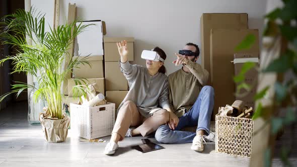 Couple in Headsets Among Boxes at New Home