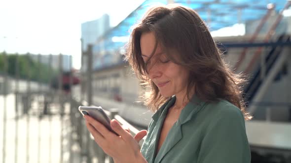 Portrait of a Middle-aged Brunette in a Green Dress. She Stands on a City Street and Checks Her alt