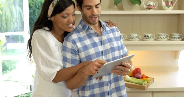 Young couple using digital tablet in kitchen alt