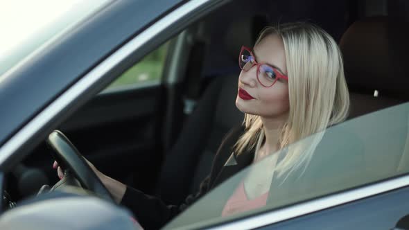 Beautiful Lady Sitting at Front Car Seat Turns and Smiles at Camera alt