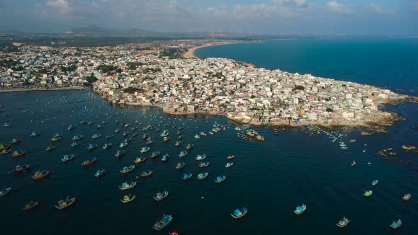 Boats moored behind small seacoast town to hide from wind, aerial view alt